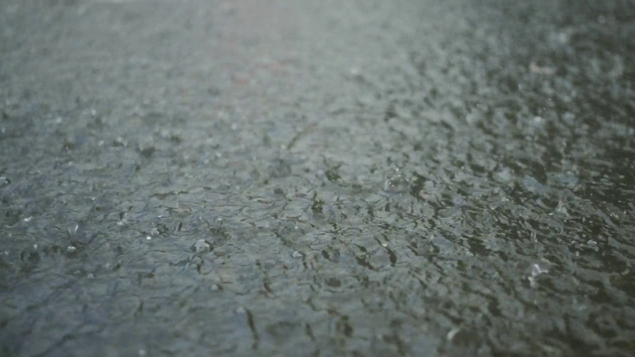 特写:雨滴落在人行道上的水坑里。城里下起了暴雨。视频素材