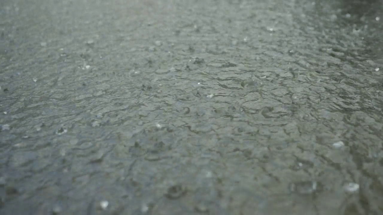 特写:雨滴落在人行道上的水坑里。城里下起了暴雨。视频素材