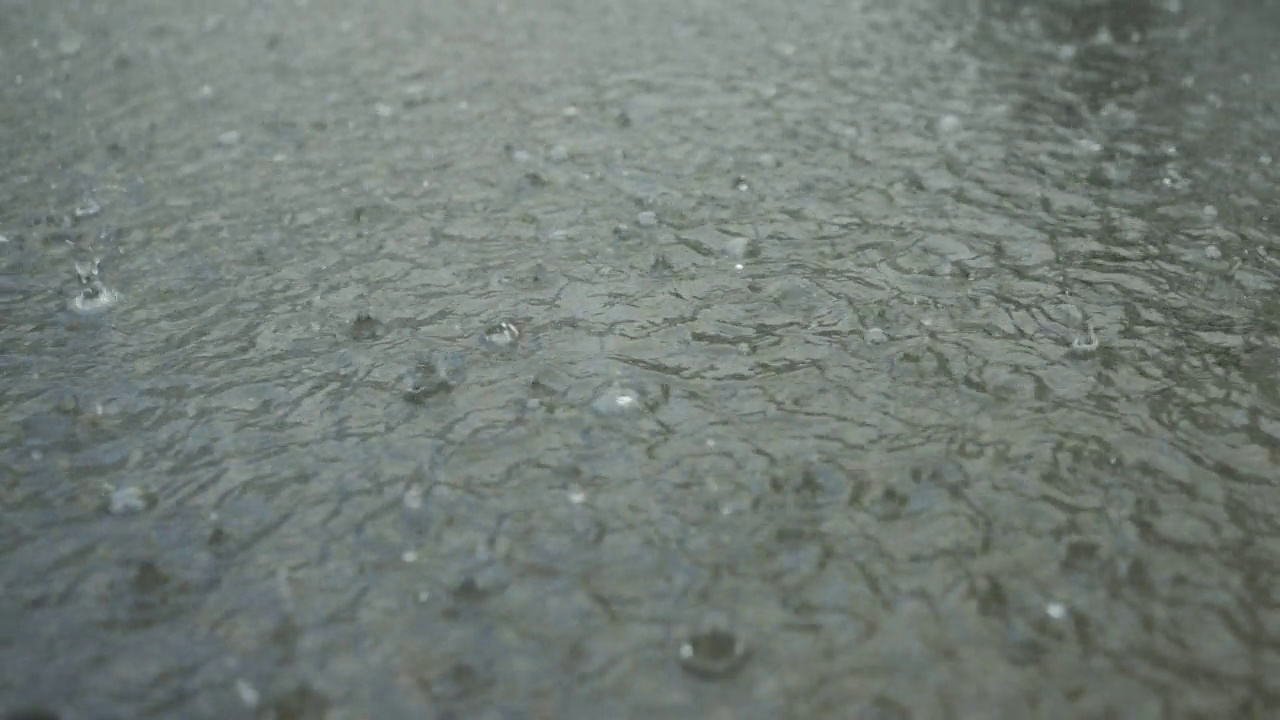 特写:雨滴落在人行道上的水坑里。城里下起了暴雨。慢动作视频素材