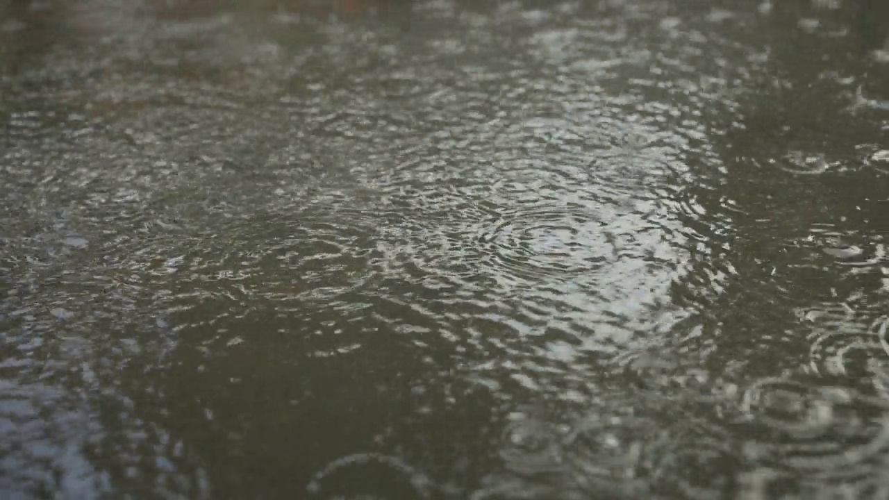 特写:雨滴落在人行道上的水坑里。城里下起了暴雨。视频素材