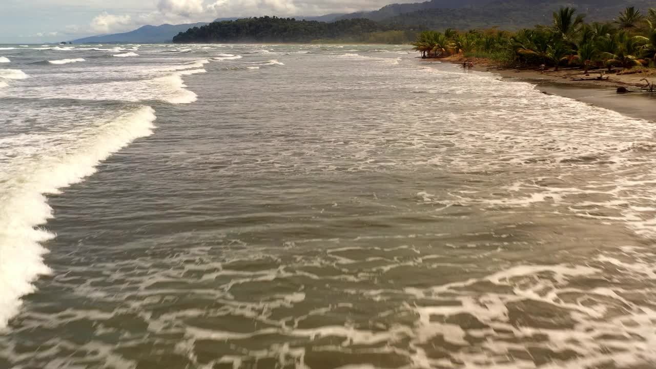 无人机飞过一个有棕榈树，海滩和大海的岛屿4k视频复制空间视频素材