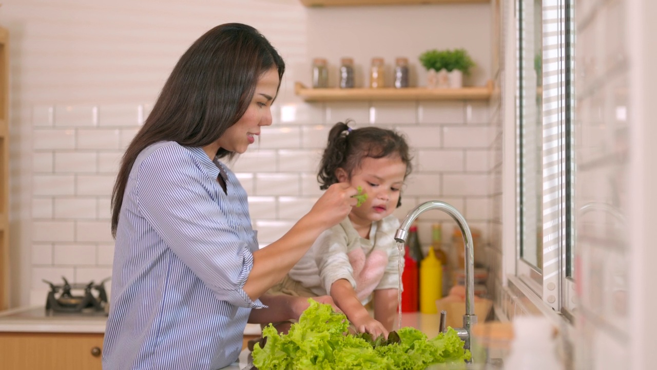 妈妈和小女儿在厨房洗菜。视频素材