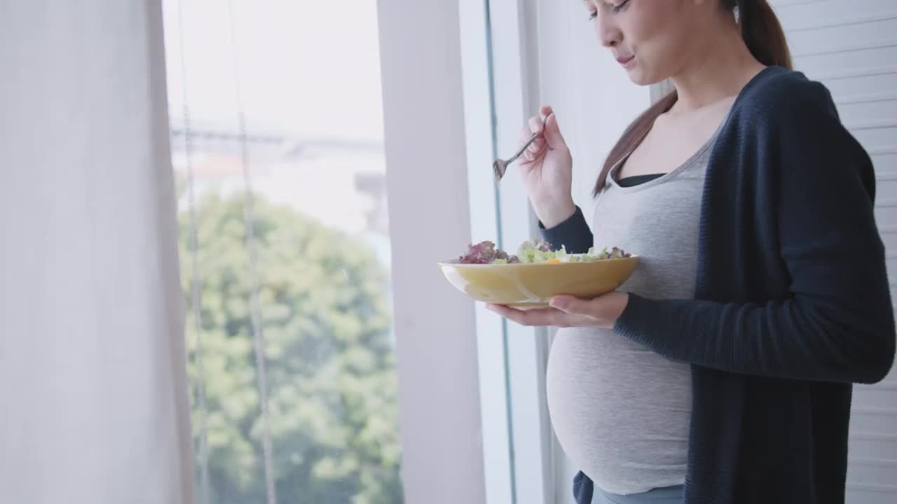 幸福的亚洲孕妇为她未出生的宝宝吃健康的食物。视频素材