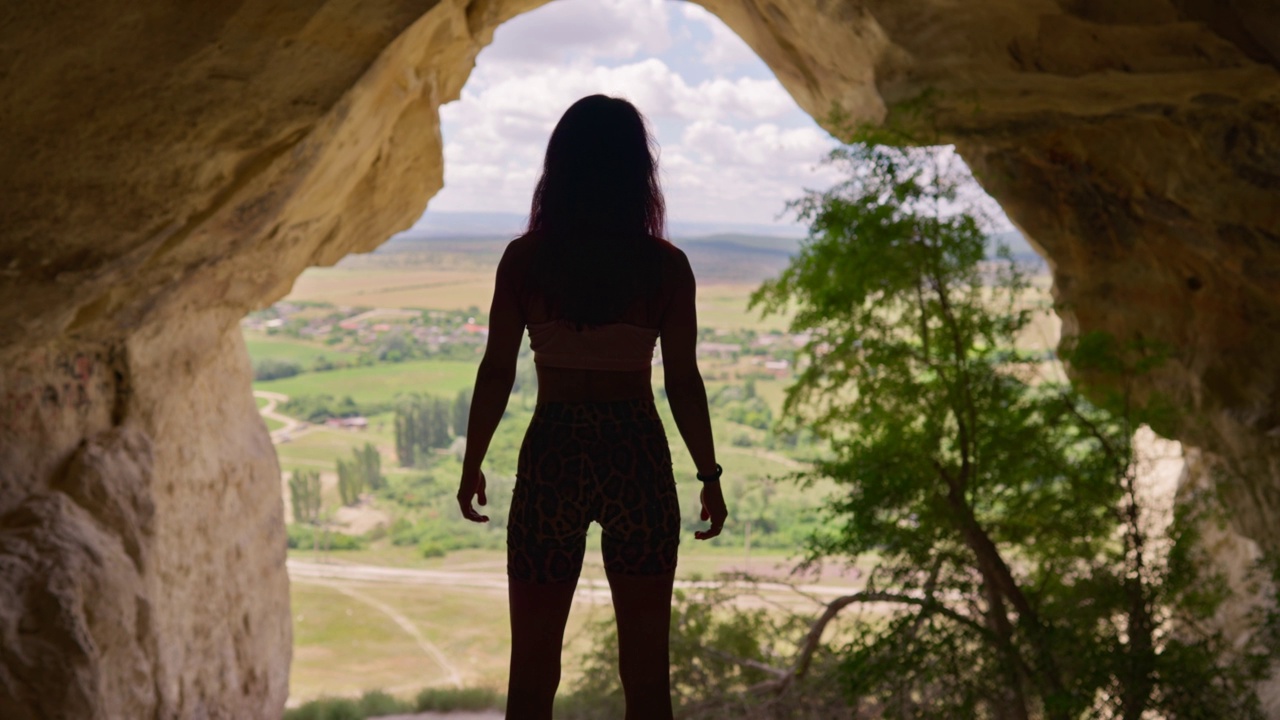 穿着运动服的苗条女人旅行者穿过洞穴走向出口视频素材