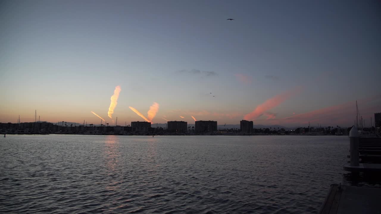 在日落的时候，鸟儿和帆船在波澜起伏的海面上飞翔，加利福尼亚视频素材