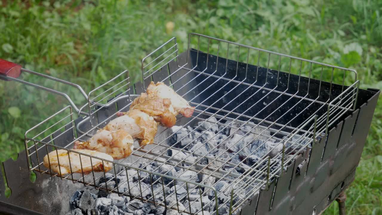 一个人把鸡肉放在烤架上。露天的炸鸡。视频素材