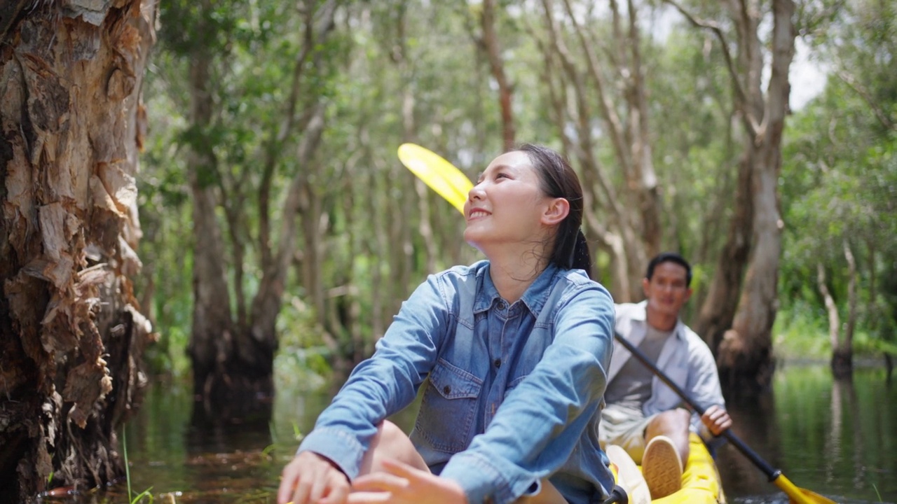 年轻的亚洲夫妇在夏季旅游假期的红树林划皮艇。视频素材