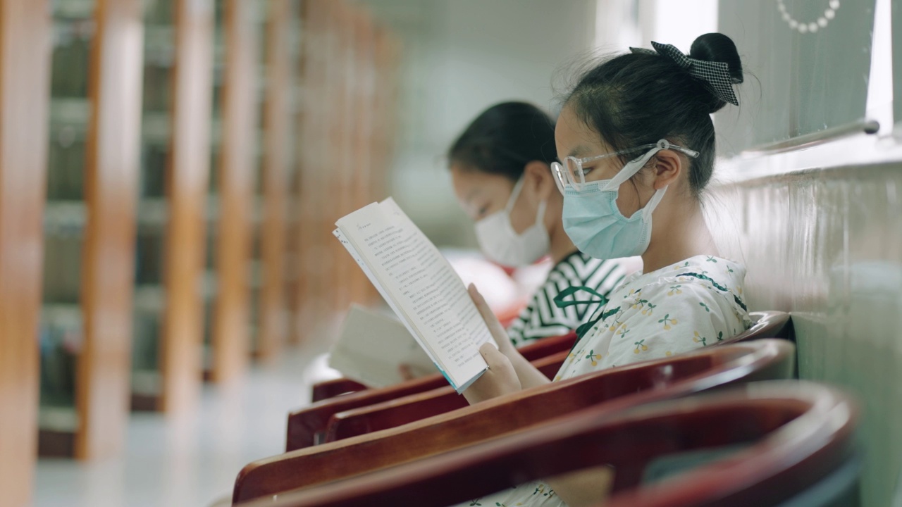 小女孩在图书馆的书架上看书视频素材