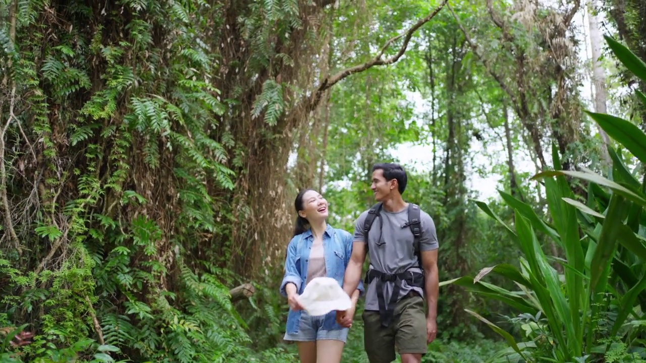 4K年轻的亚洲夫妇一起在热带森林徒步旅行。视频素材