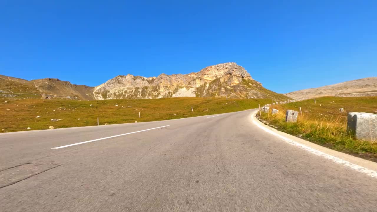 在一个阳光明媚的日子里，驾车行驶在蜿蜒的山路上，穿过风景如画、充满活力的风景视频素材