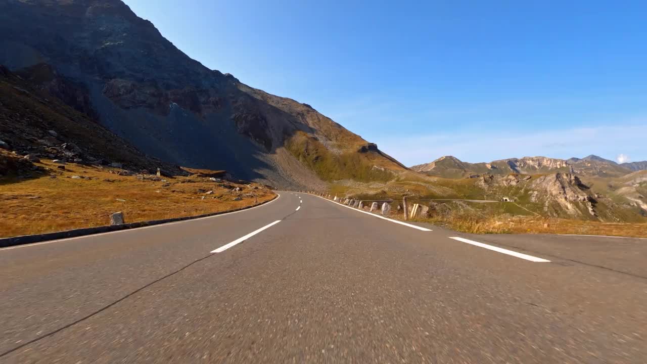 在一个阳光明媚的日子，在山间公路上驾车穿越如画的风景视频素材