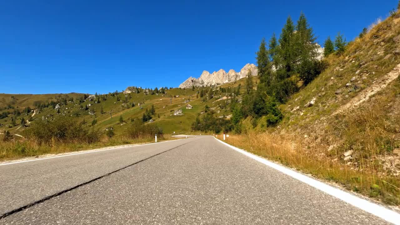 在一个阳光明媚的日子里，驾驶一辆乘用车在山间公路上穿越如画的风景，以第一人称视角视频素材