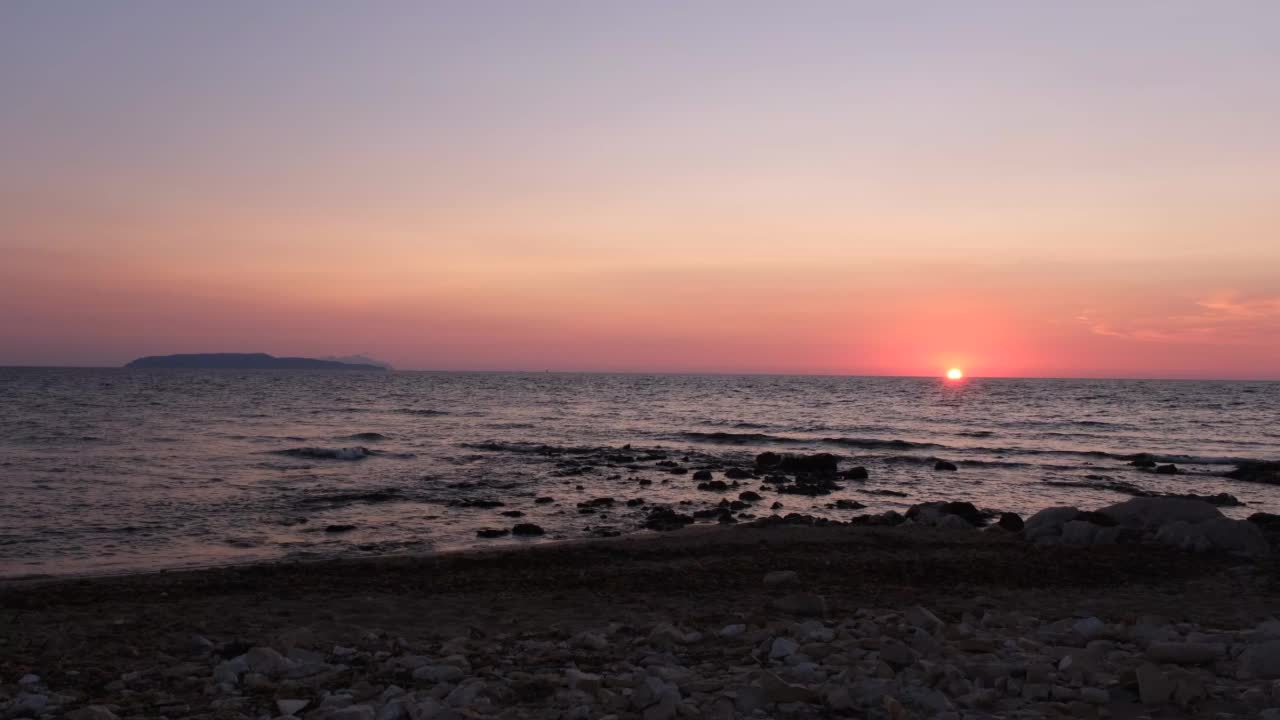 海岸线上美丽的日落。太阳即将从天空中消失，平静的海浪在海边，意大利西西里岛。视频下载