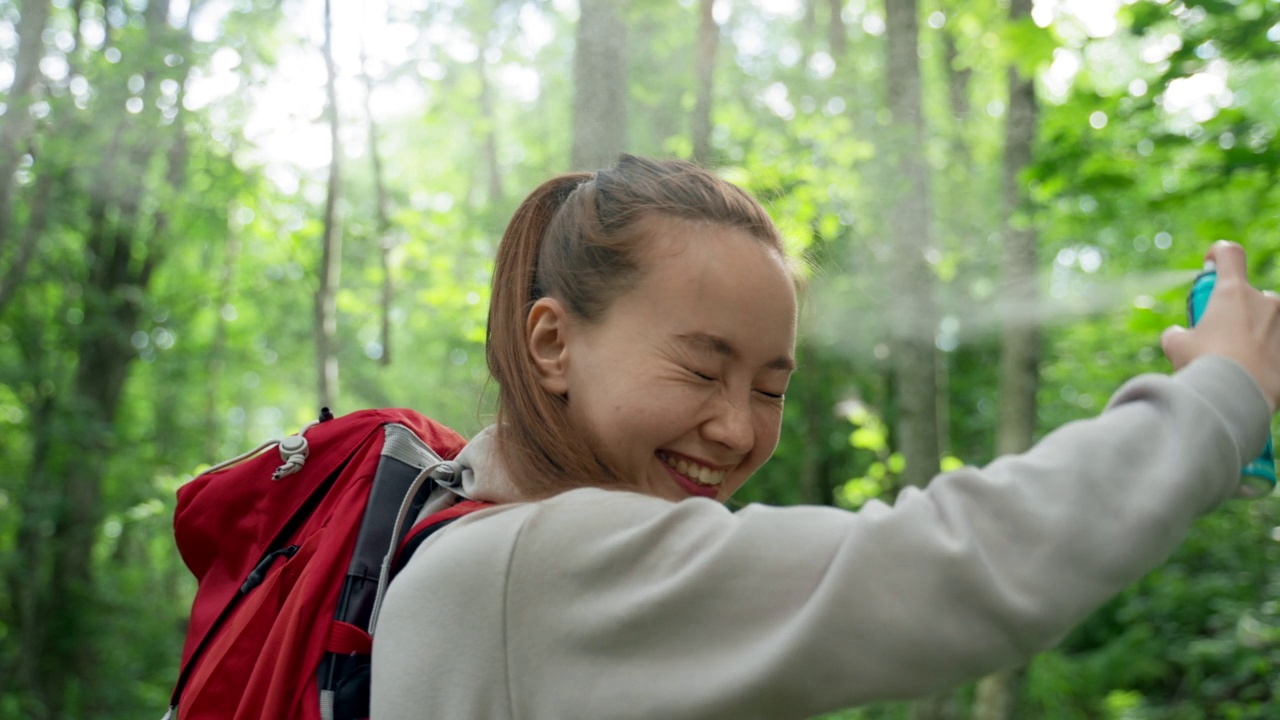 年轻女子使用蚊子喷雾对脸闭上眼睛特写视频素材