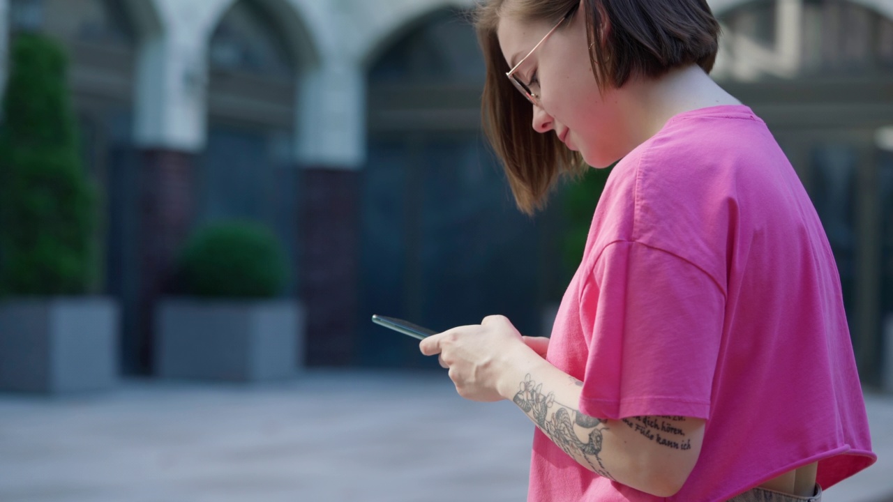 年轻女孩使用手机坐在户外办公大楼背景视频素材