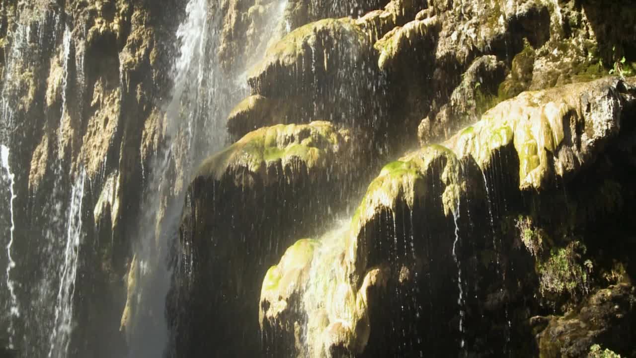 水从岩石上流过，森林里的树。悬崖和瀑布水。流。视频素材