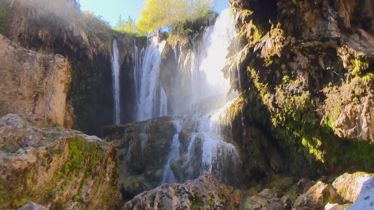 水从岩石上流过，森林里的树。悬崖和瀑布水。视频素材