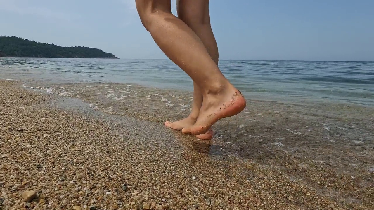 赤脚在沙滩上行走的年轻女子视频素材