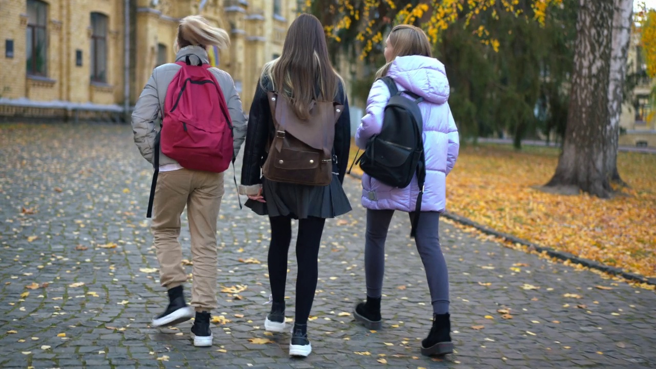 后视图宽镜头轻松的学生女孩散步到大学户外交谈。自信的白人青少年朋友在校园散步聊天的跟踪镜头。教育友谊理念。视频素材