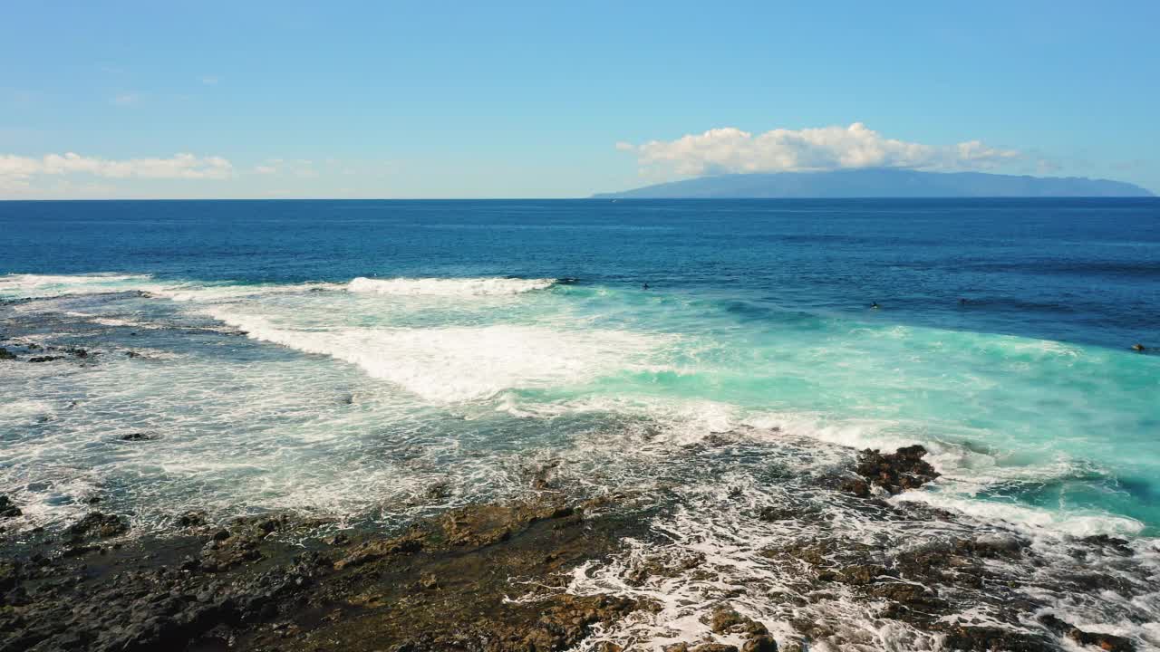 深蓝色的海浪冲击着特内里费岛黑色的火山海岸。电影镜头:蓝绿色的海水猛烈地涌起，飞溅在一个奇异岛屿的岩石海岸上视频素材