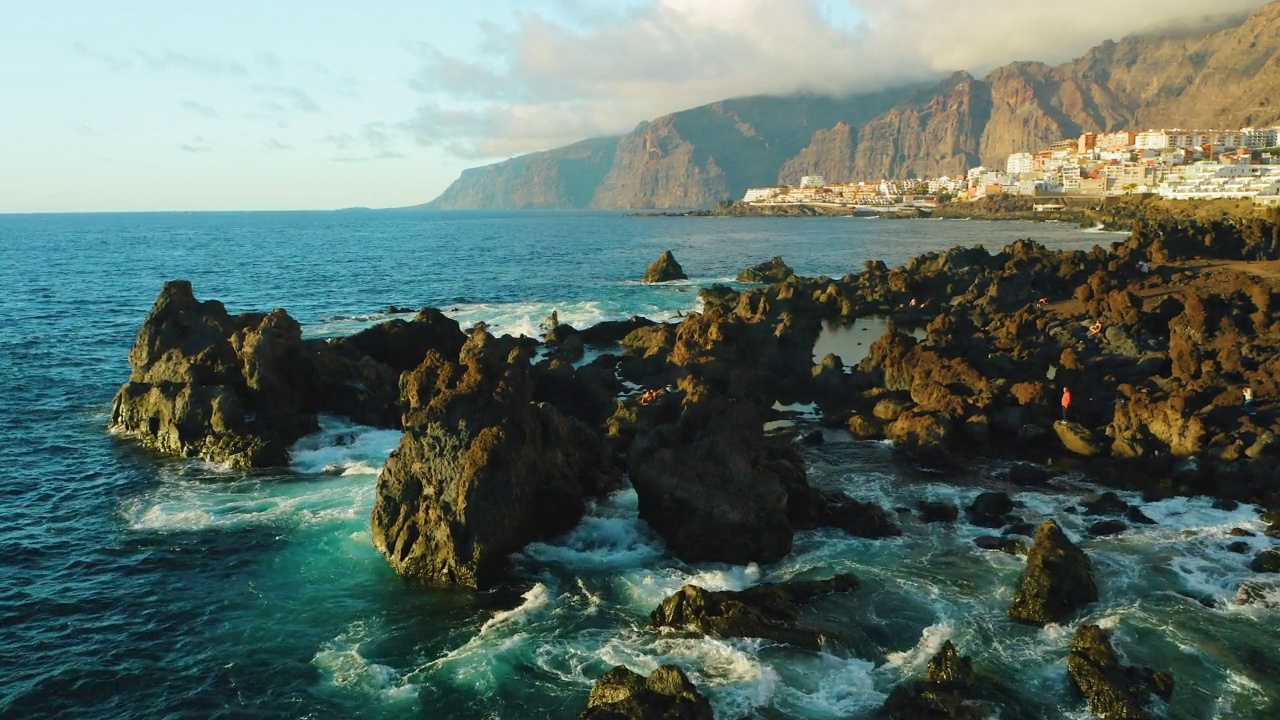 旅游的地方。航拍夕阳照射在海浪和岩石上。特内里费岛，加那利岛，圣地亚哥港，Charco el Diablo或魔鬼自然池。熔岩流，火山奇形怪状的石滩视频素材