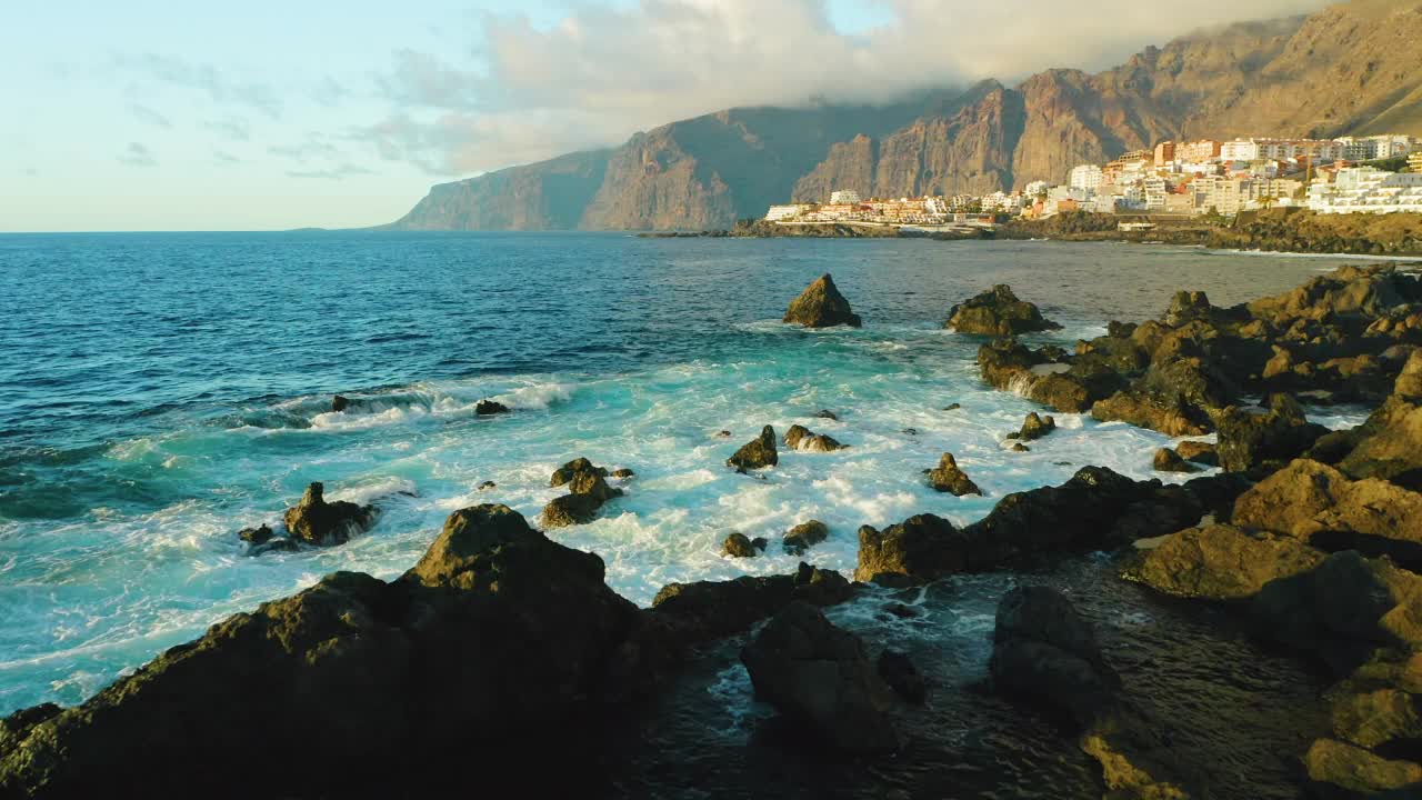 旅游的地方。航拍夕阳照射在海浪和岩石上。特内里费岛，加那利岛，洛斯巨人悬崖，圣地亚哥港，魔鬼的天然池塘。熔岩流，火山奇形怪状的石滩视频素材