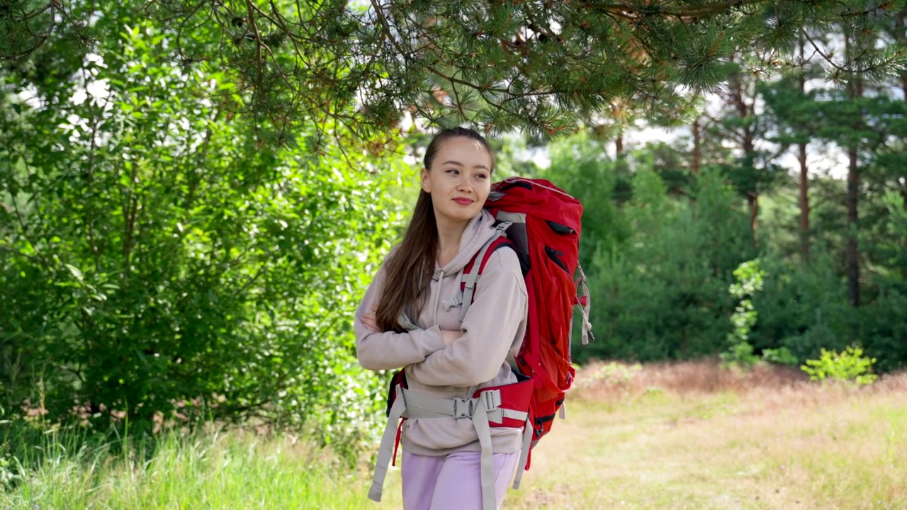 快乐的年轻女子徒步森林微笑在阳光明媚的林间空地视频素材