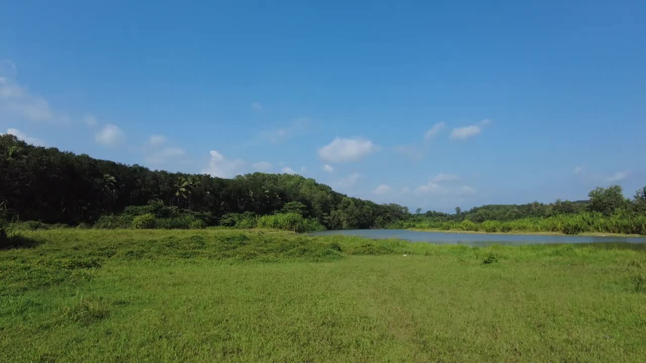 绿色的草地和蓝色的天空背景，阿鲁维卡拉大坝水库，Thiruvananthapuram，喀拉拉邦视频素材