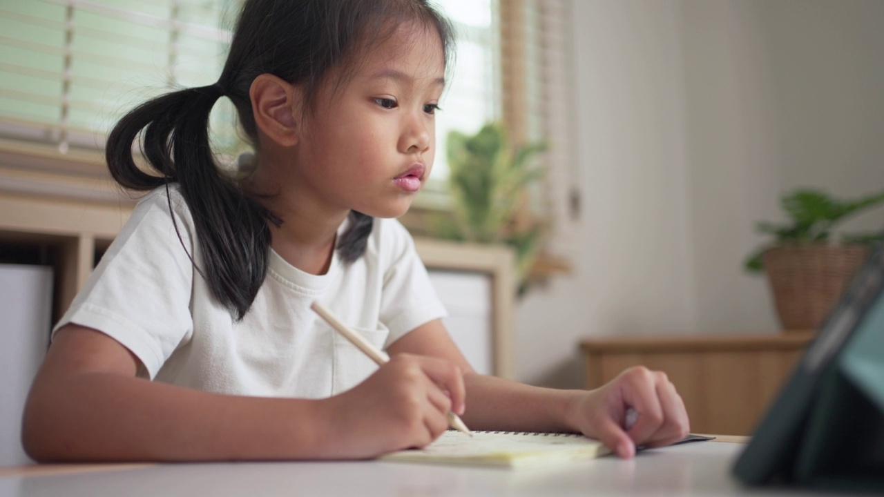 一个在家用平板电脑上网学习的女孩。孩子在线教育视频素材