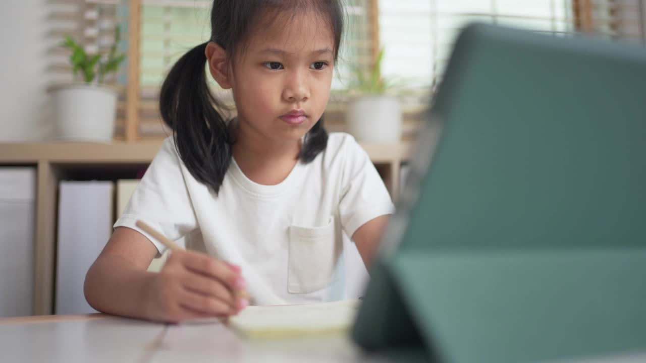 一个在家用平板电脑上网学习的女孩。孩子在线教育视频素材