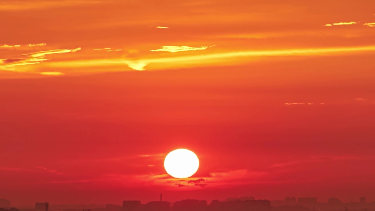 黎明的天空中，一轮红彤彤的大太阳，一幅炎热的夏日风景画。阳光明媚的清晨天空视频素材