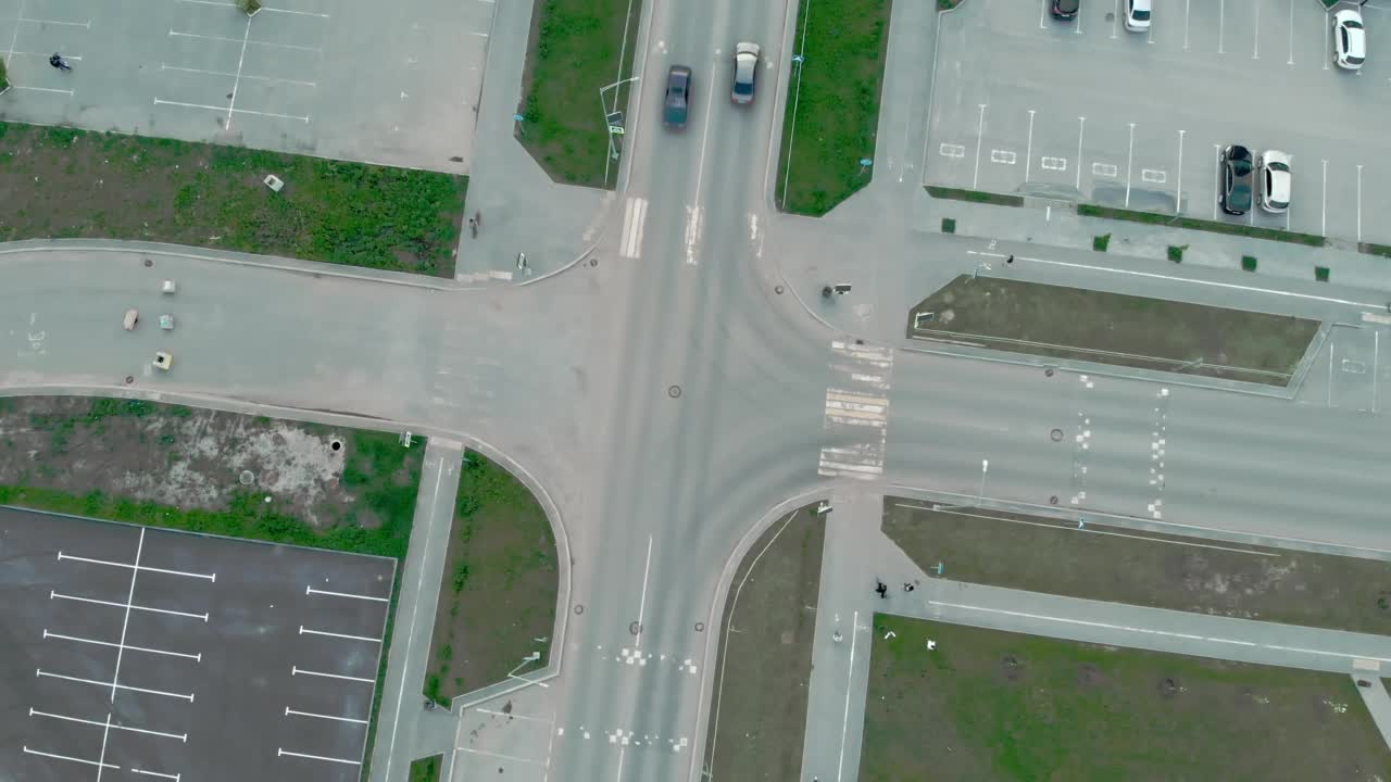 无人机在汽车行驶和城市居民过马路的十字路口上空飞行。从道路的俯视图上看，这是一个睡觉的地方，有一个路口，汽车沿着它移动。视频素材