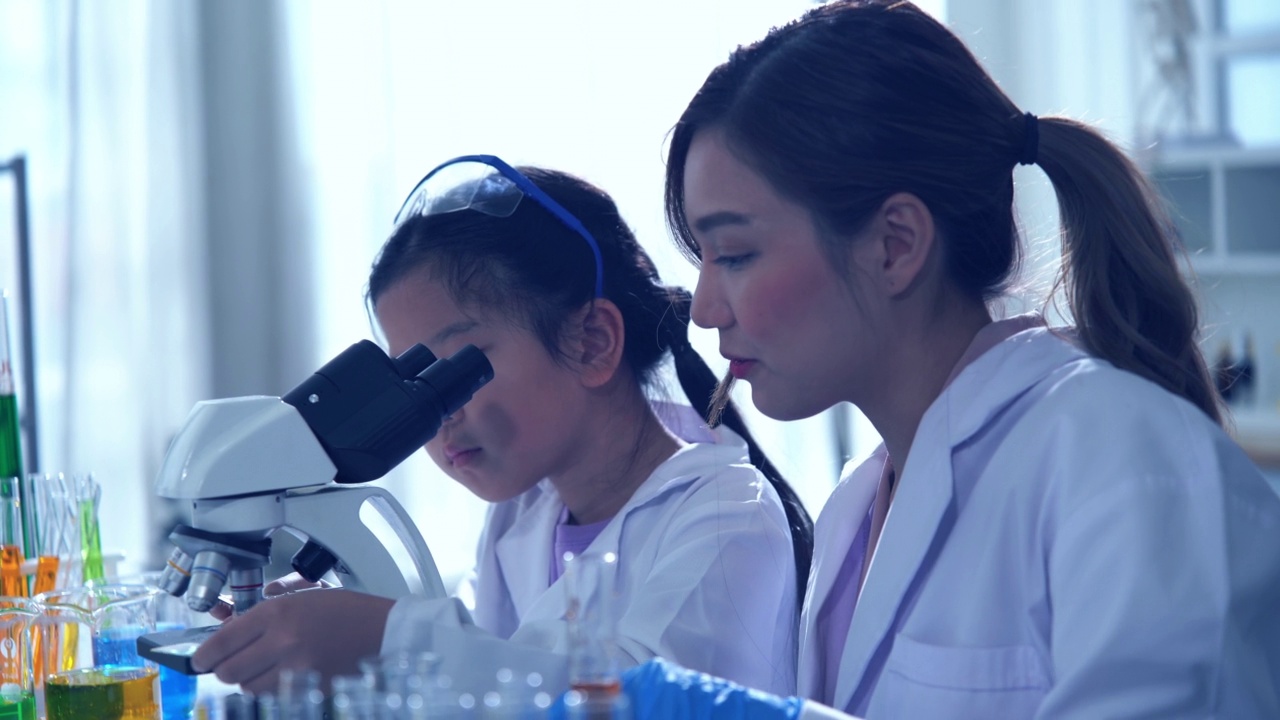 年轻的女教师和阿塞恩女孩私立小学STEM学校的学生进行科学实验视频素材