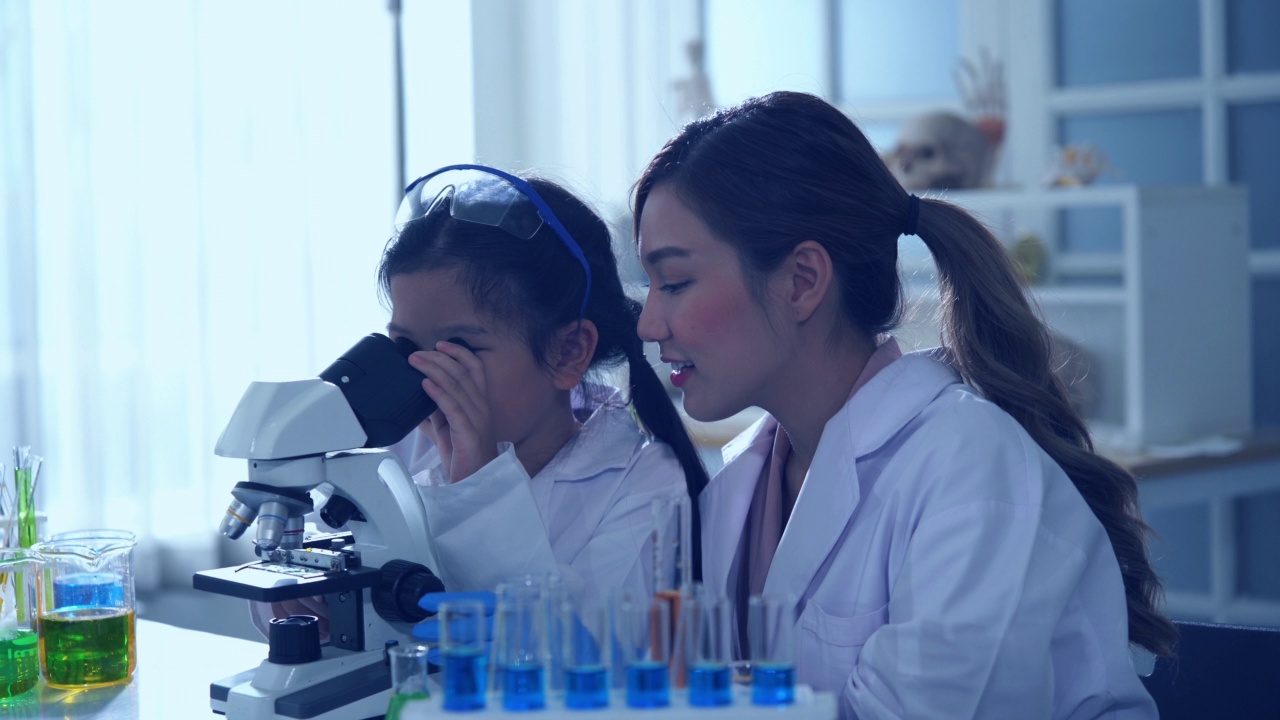 年轻的女教师和阿塞恩女孩私立小学STEM学校的学生进行科学实验视频素材