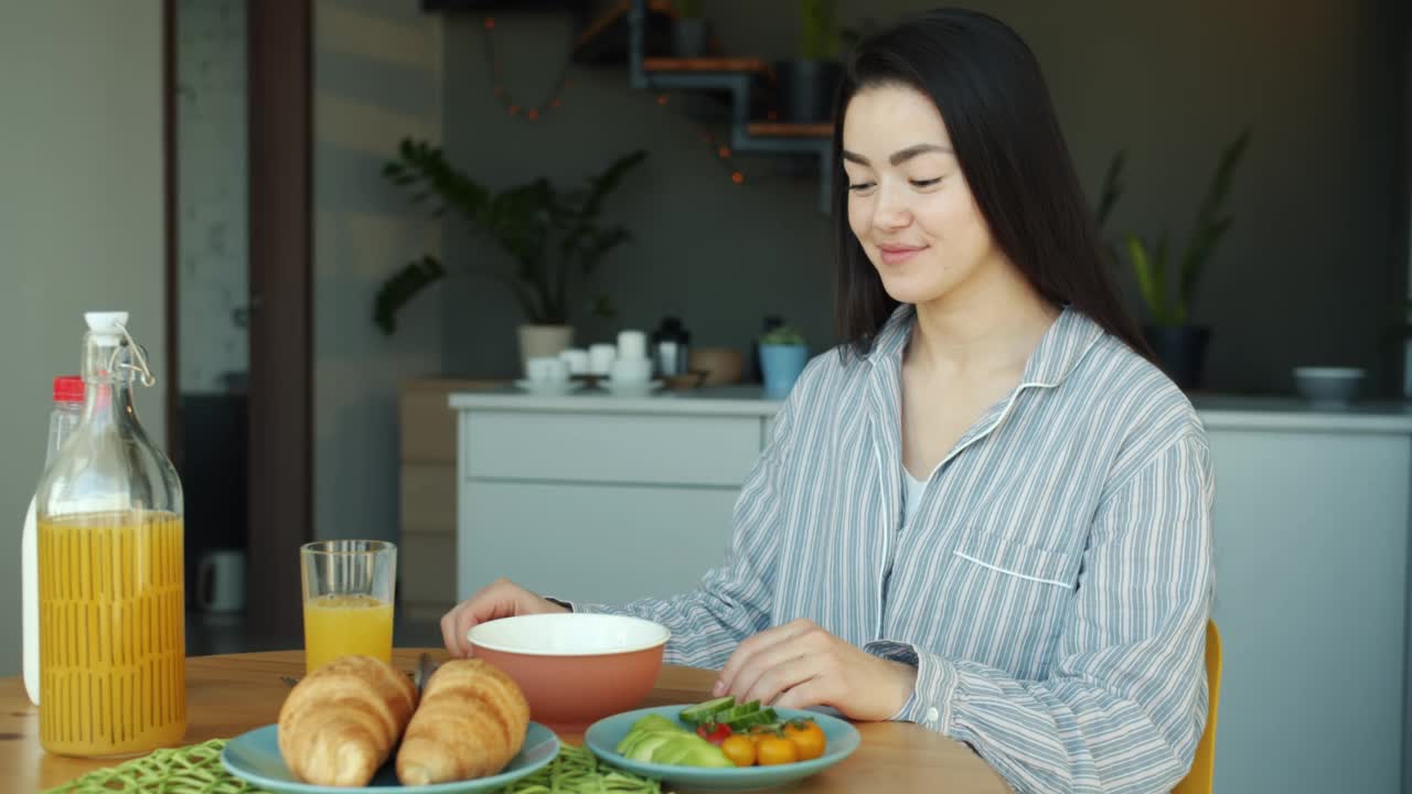 幸福的亚洲女人的肖像吃麦片早餐在家里的厨房视频素材