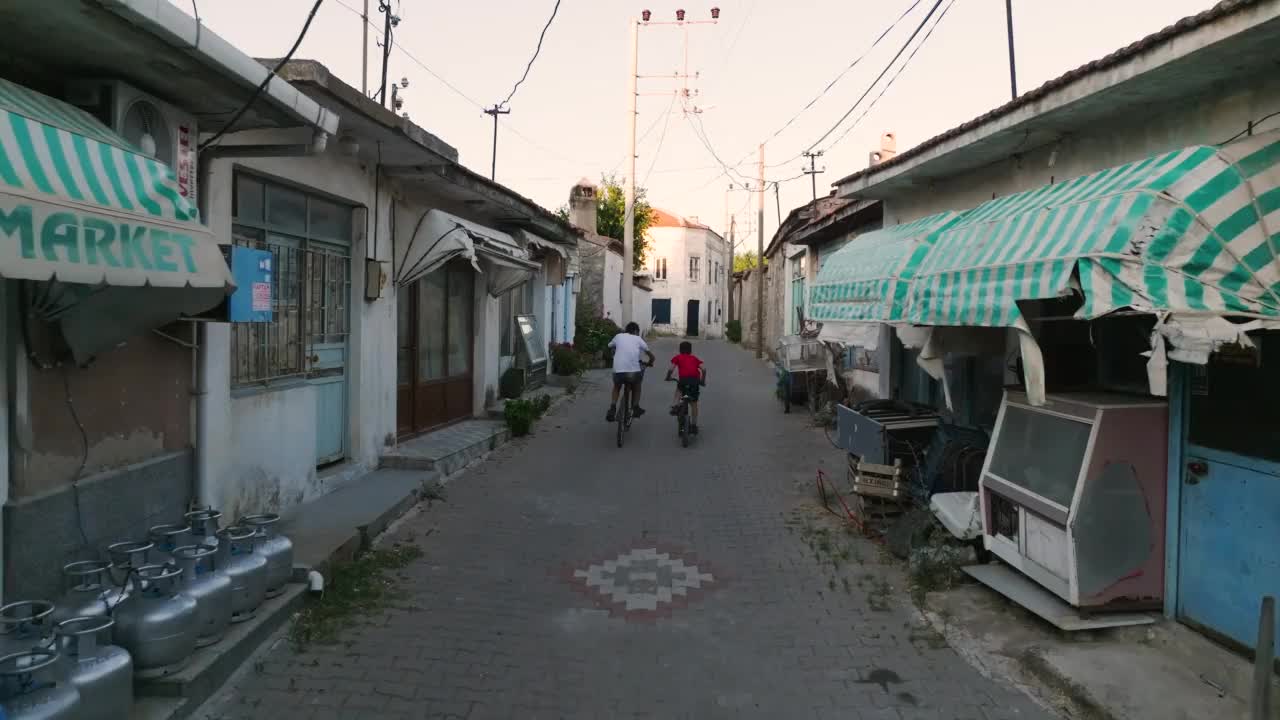 夕阳西下两个孩子在街上骑自行车，在街上玩游戏，在一个老村里玩孩子，骑自行车的孩子，欢快的骑自行车的孩子，视频素材