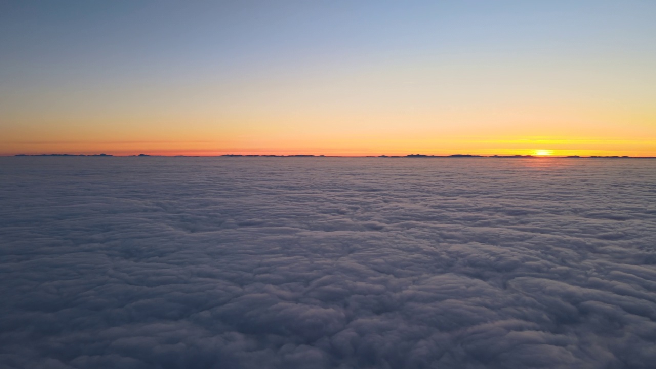 高空鸟瞰图，密集而蓬松的积云在傍晚飞行。从飞机窗口看到的令人惊叹的日落视频素材