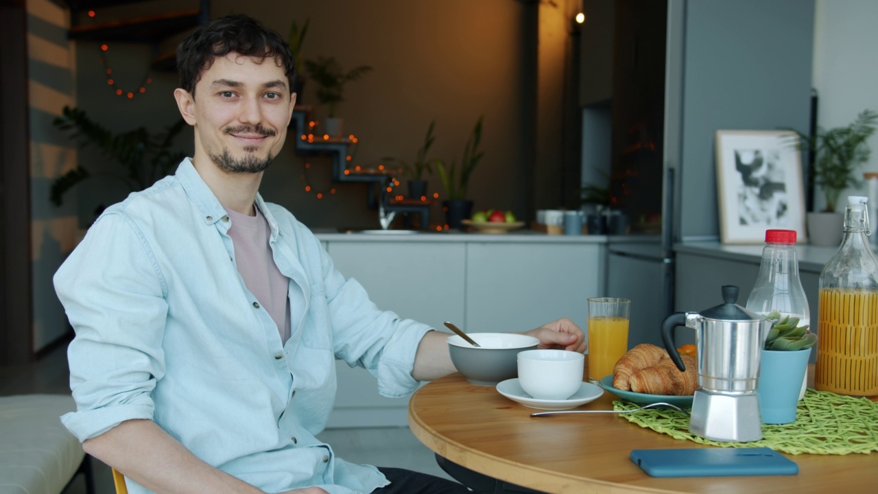 慢动作肖像的混血儿种族男子坐在厨房的桌子上与食物微笑视频素材