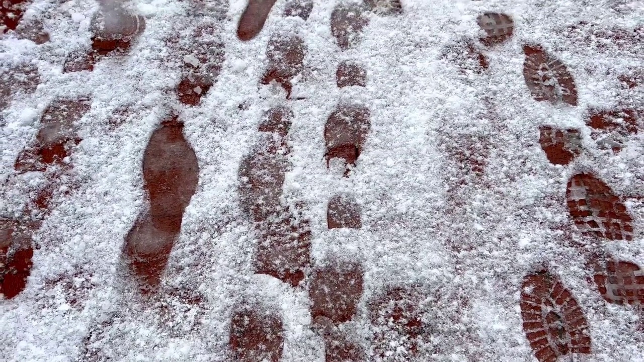 脚印在冰雪覆盖的人行道上视频素材