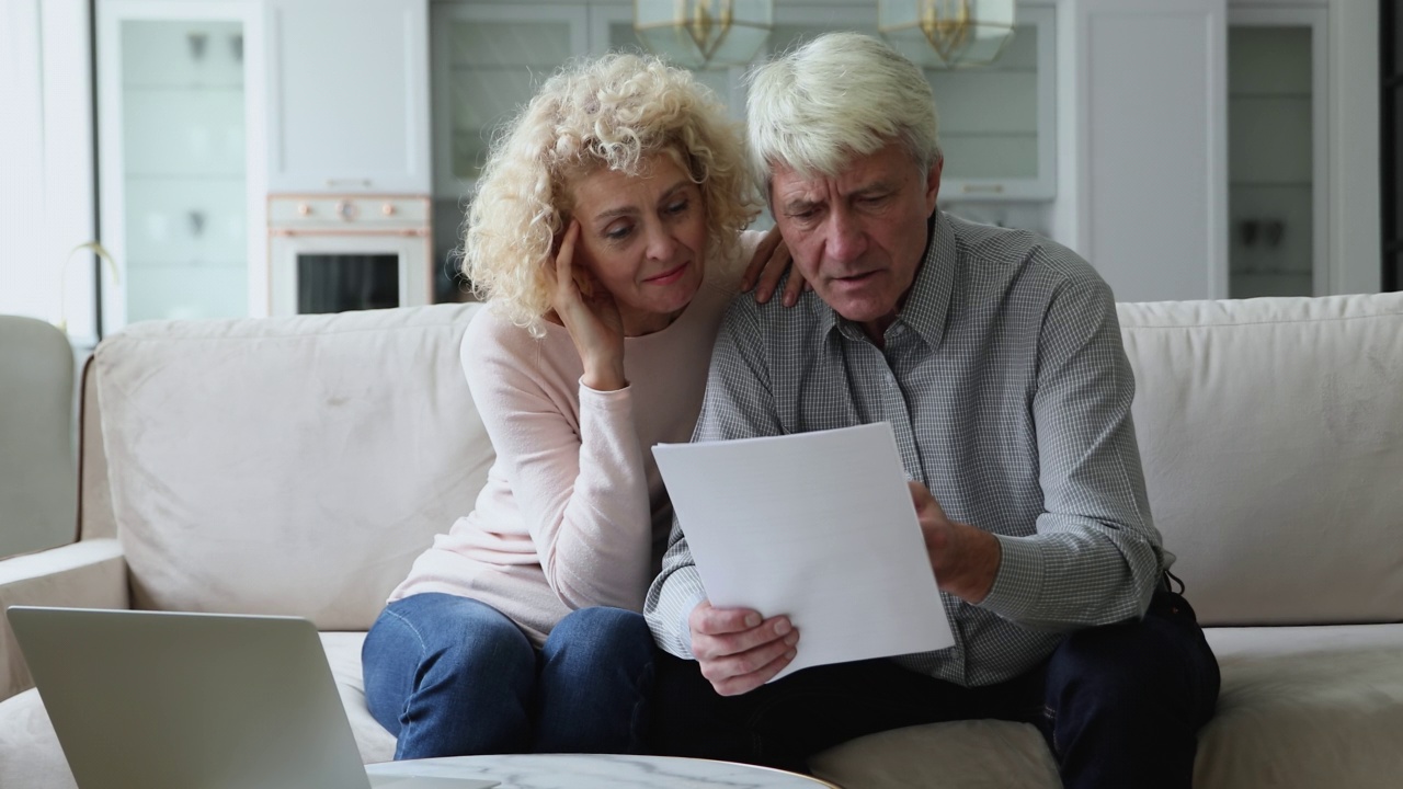 成熟的退休夫妇阅读文件单，保险，医疗协议视频素材