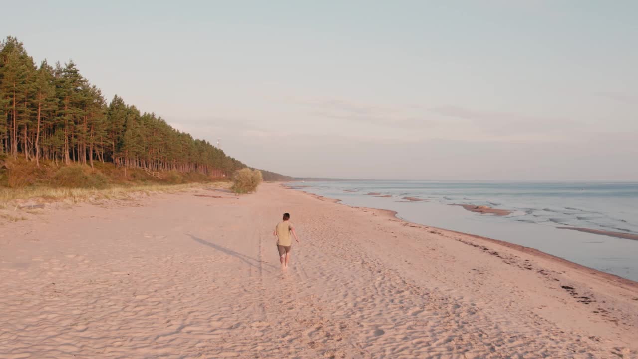 年轻的跑步者沿着日出后的海滩风景跑步视频素材