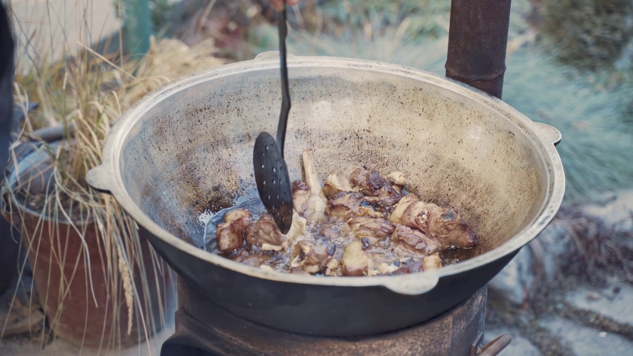 厨师用漏勺在大锅里混合肉类。视频素材