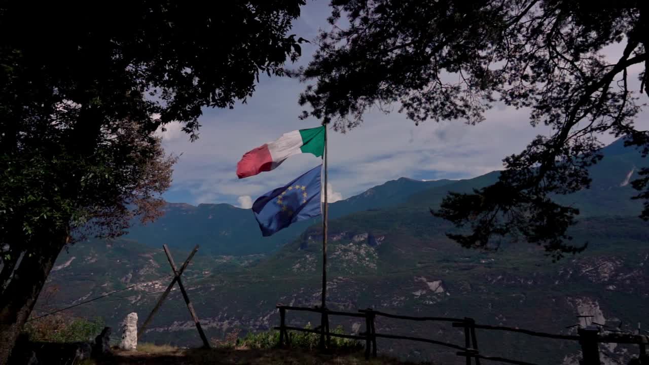 意大利和欧洲的旗帜在风中飘扬，在山间，变成森林的空地视频素材