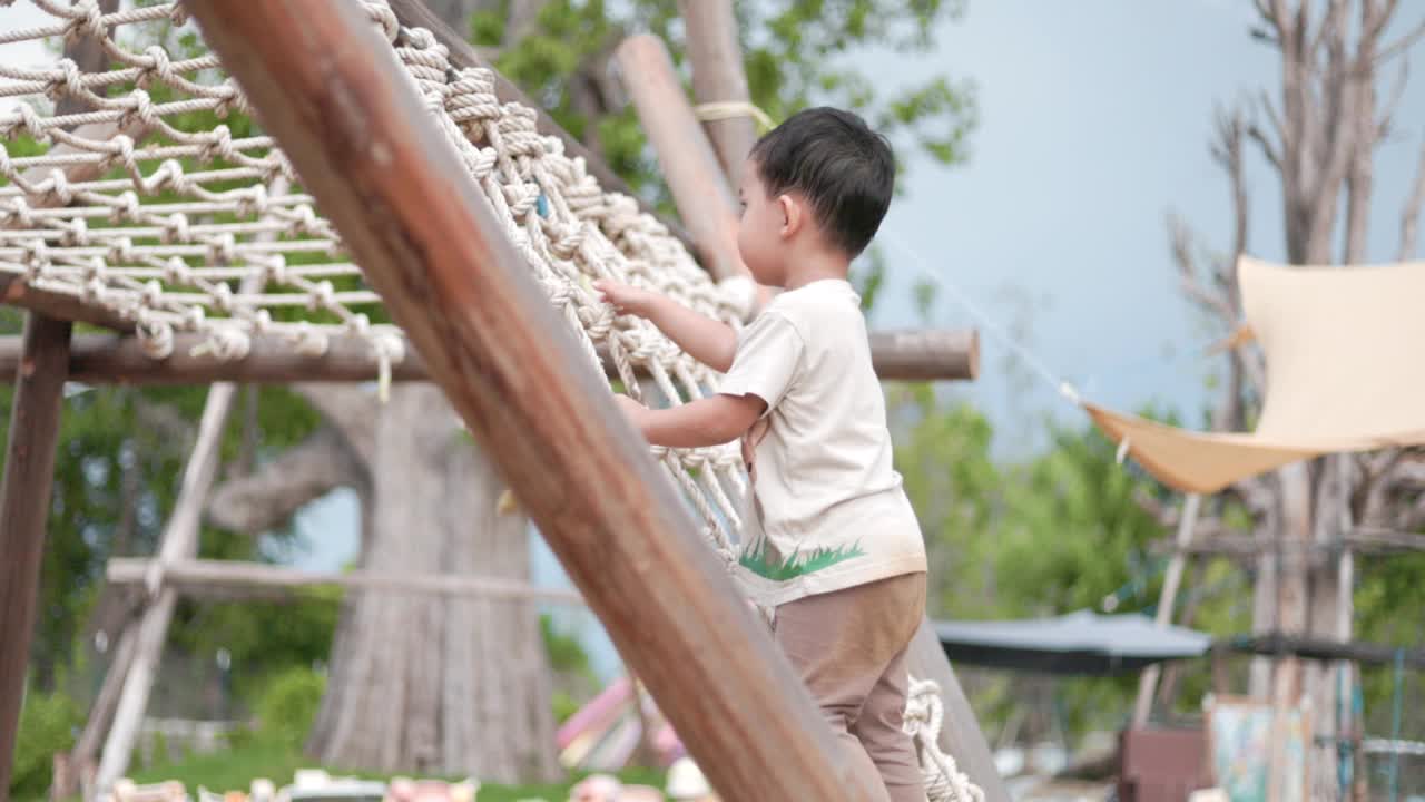 小男孩爬上绳梯攀爬方格架视频素材