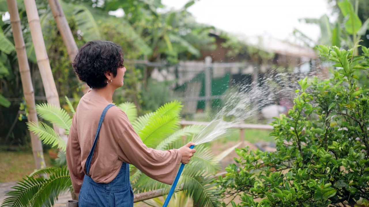 农妇在花园里给植物浇水很开心视频素材