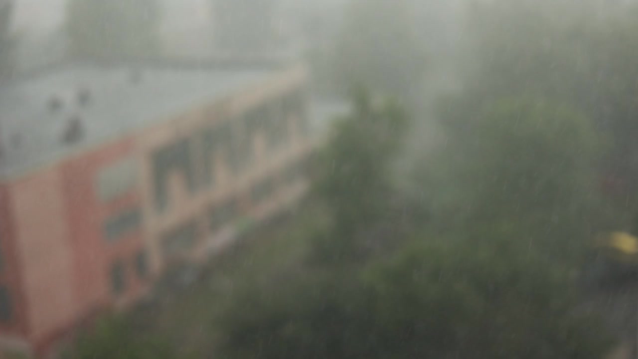 大雨慢慢地打在窗户上，还打着雷。强烈的雷雨带着雨水穿过窗户玻璃。暴雨,雨季。窗外的屋顶视频素材