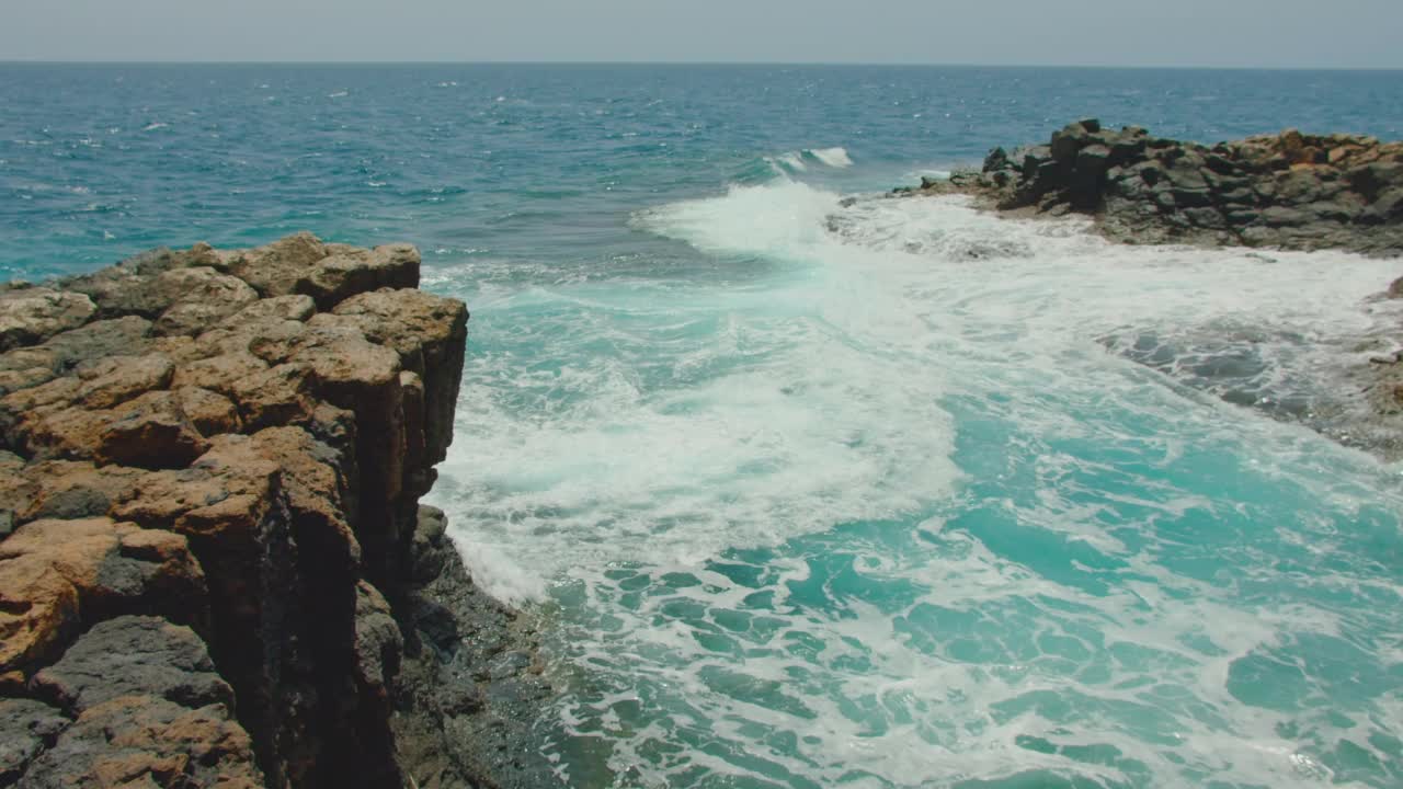 Fuerteventura,加那利群岛。天然游泳池。海浪冲击着空荡荡的岩石黑色海滩。火山石的特写，水花四溅。Castillo Caleta de Fuste镇附近。视频素材