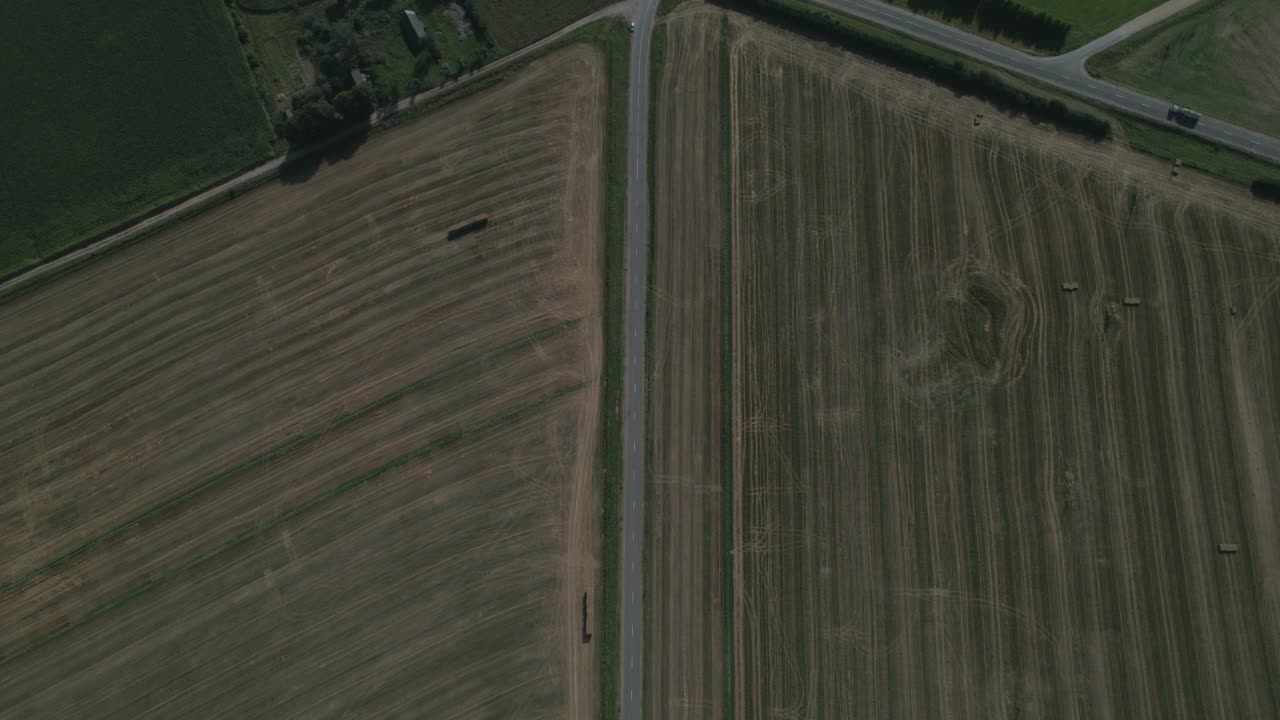 半卡车行驶在农村地区的道路上。背景中的农田和山丘视频素材