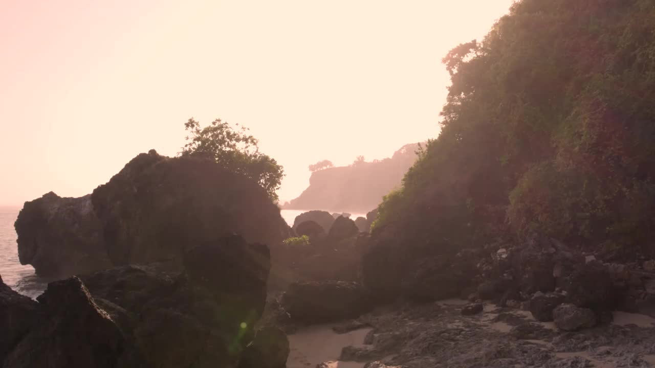 无人机拍摄的日落时分，印尼巴厘岛波涛起伏的岩石海滩视频素材