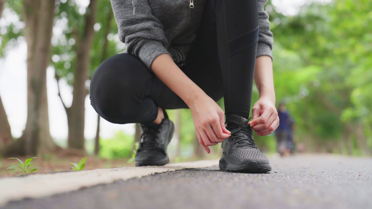 女人系鞋带的特写。亚洲女性运动健身运动员准备在公园户外慢跑视频素材